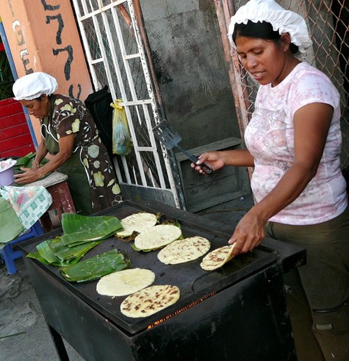 Women preparing and serving corn tortillas stuffed with fresh cheese and banana leaf.