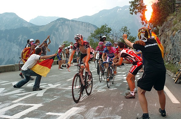 Tour de France with cyclists and spectators excited as the bikers mount hill during race.