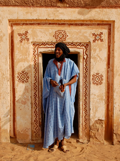 Mauritanian man in blue robe standing in a doorway.