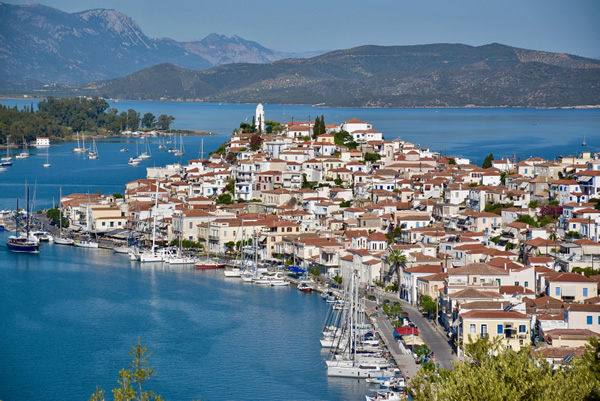 Senior Travel in Poros with view of town surrounded by water and hills. 
