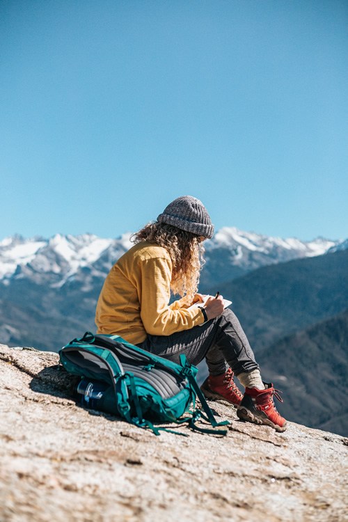 Young woman doing some travel writing on a mountaintop.