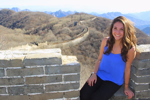 Author sitting on the great wall of China with landscape.
