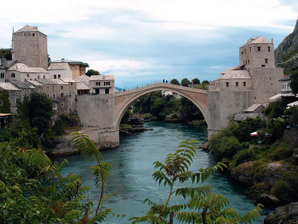 The Old Bridge of Mostar with pedestrians crossing over the river.