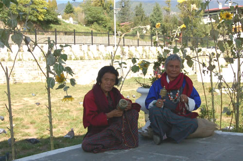 A woman and man seated in Bhutan reciting prayers.