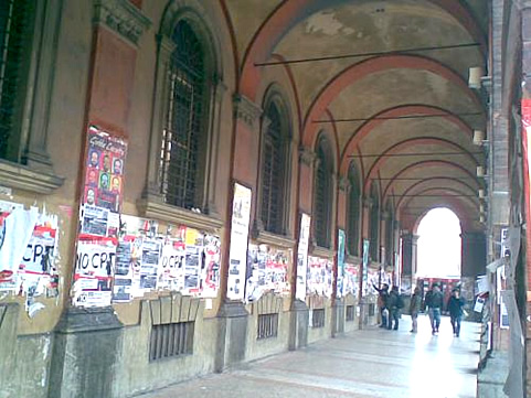 Bologna portico with students and announcements.