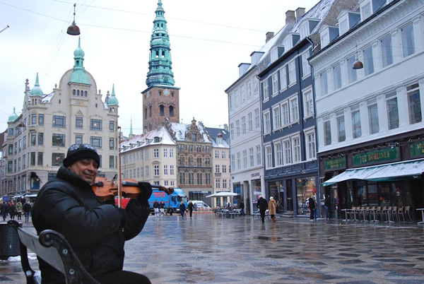 An immigrant playing a violin on a bench in Copenhagen, Denmark.