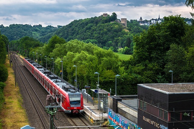 Local train pulling into the station among green hills.