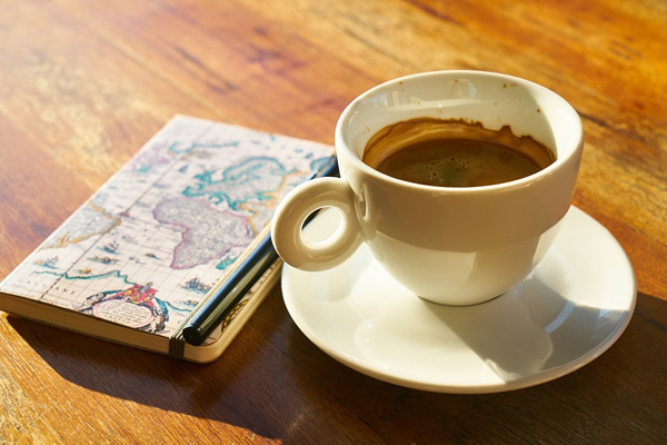 A writing journal next to a cup of coffee.