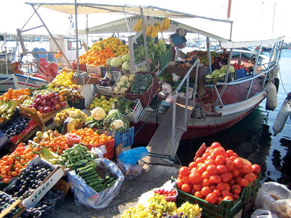 Market with fruits and vegetable sold from a boat on Aegina Island, Greece.