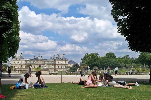 Students laying in the grass of Jardin de Luxembourg park in Paris.